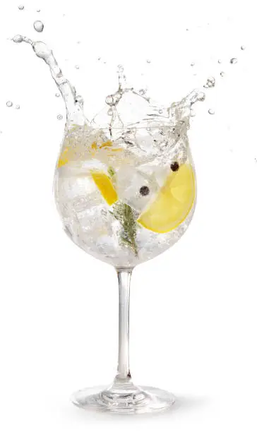 gin tonic garnished with lemon and rosemary splashing on white background