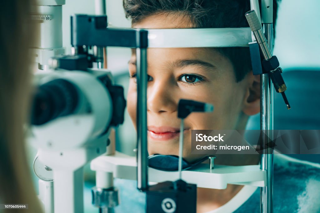 Eye Exam. Ophthalmology, slit lamp exam, school boy having his eye sight checked Eye Exam. Ophthalmologist examining boy's eyes with slit lamp Child Stock Photo