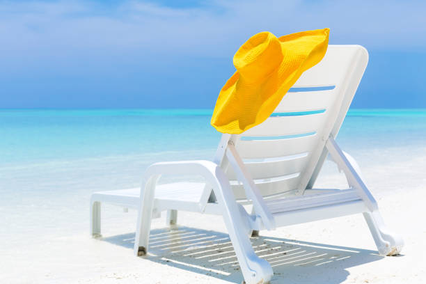 A pair of blue beach chairs with umbrellas sitting on white sandy beaches in front of the ocean on a sunny day.