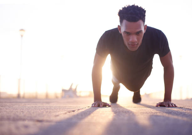 Shot of a handsome young man taking his exercise routine outdoors