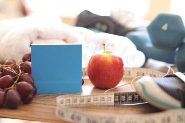 New Year's Resolution to Get Healthy! New year's resolution to get healthy in the coming year! Group of objects includes: note pad, fruit, tape measure, ear buds, athletic shoes, dumbbells, water bottle and towel. Concept of an individual preparing items for an exercise. 2019 new year resolution stock pictures, royalty-free photos & images