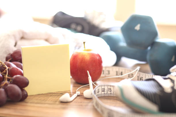 New Year's Resolution to Get Healthy! New year's resolution to get healthy in the coming year! Group of objects includes: note pad, fruit, tape measure, ear buds, athletic shoes, dumbbells, water bottle and towel. Concept of an individual preparing items for an exercise. 2019 new year resolution stock pictures, royalty-free photos & images