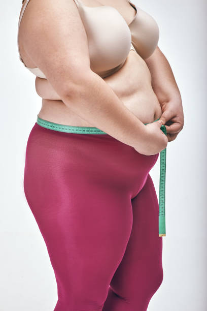 istock Woman is measuring her belly on white background 1070618326
