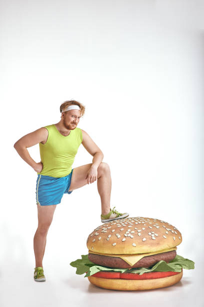 istock Red haired, bearded, plump man put his leg to a huge sandwich 1070620500