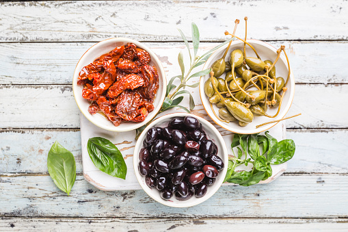 Italian appetizer from above. Mediterranean snack assortment. Black olives, capers, olive oil, and sun-dried tomatoes top view.