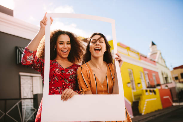 istock Excited women outdoors with a photo frame 1070639752