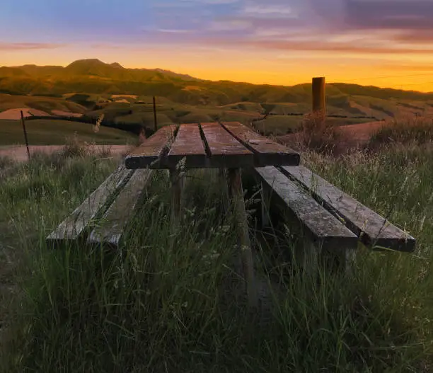 Blurred Focused Beautiful twilight picturesque farmland view of Middle Valley, Canterbury, New Zealand. Wooden bench and table in natural morning light, refreshing rural air at sunrise.