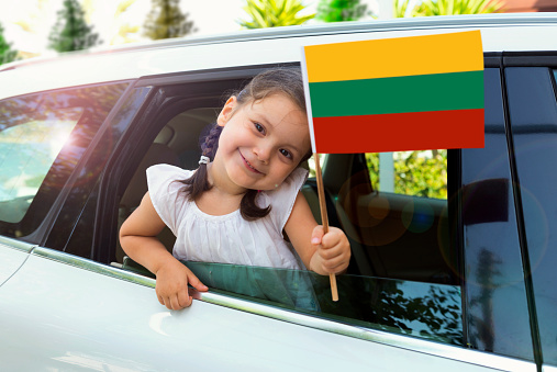 Girl holding Lithuanian Flag in the car.