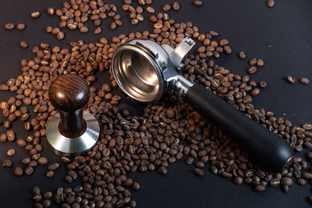 istock Portafilter and tamper in coffee beans on black background. Coffee making. 1070662786