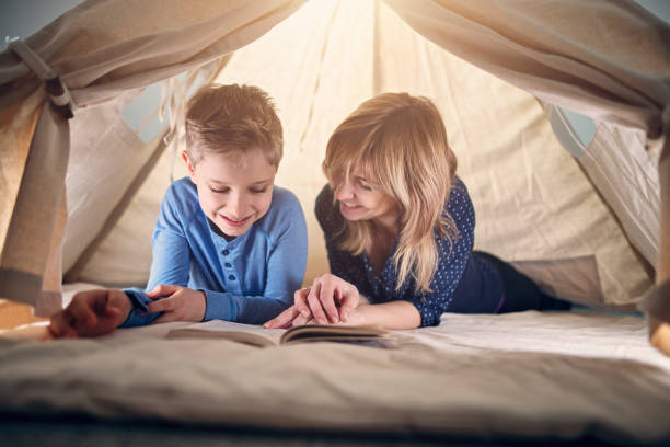 mutter und sohn ein buch im tipi-zelt - tipi bett stock-fotos und bilder