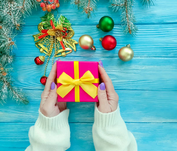istock branch tree, female hand gift box snow on wooden background 1070673692