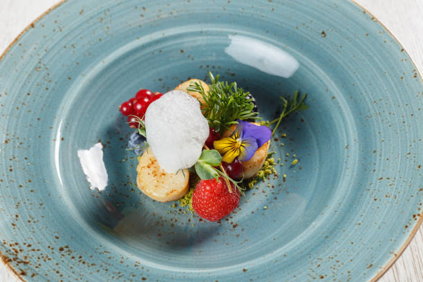 istock Fried pears on a bed of ground pistachios, garnished with egg mousse on a blue plate 1070674850
