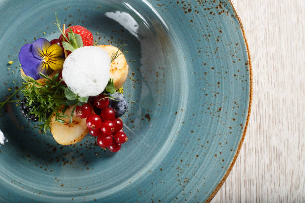 istock Fried pears on a bed of ground pistachios, garnished with egg mousse on a blue plate 1070674866
