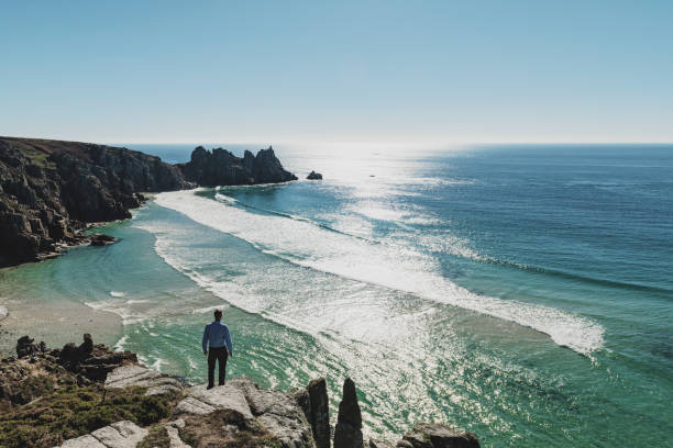 istock Man stood looking out over Pedn Vounder Beach towards Logan's Rock, Cornwall 1070685796