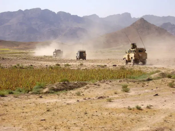Multiple Canadian armoured vehicles driving through the desert of Afghanistan.