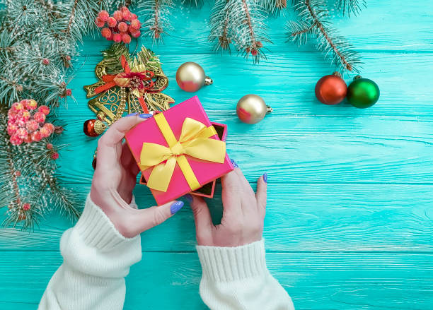istock branch tree, female hand gift box snow on wooden background 1070689120