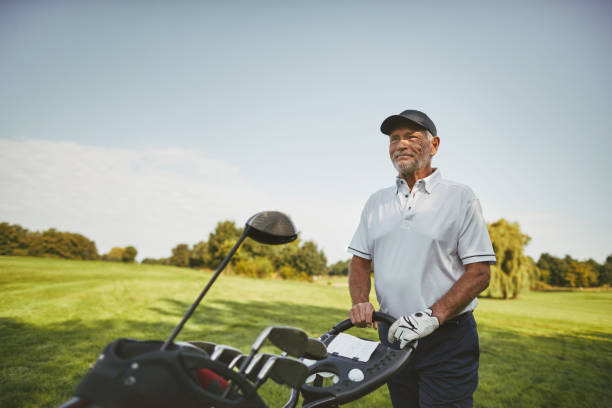 istock Smiling senior man pushing his clubs on a golf course 1070689460