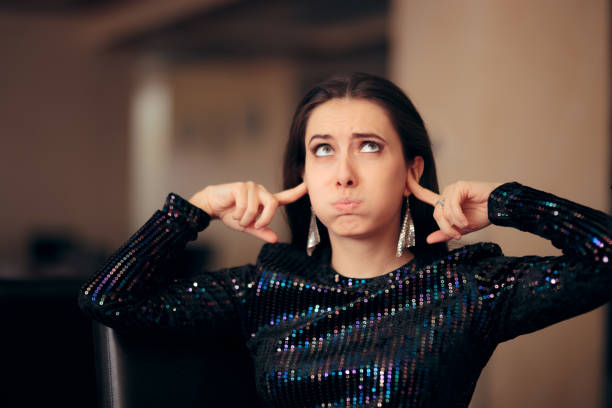 Unhappy Girl Hating the Loud Bad Music at a Party Woman plugging her ears trying to cover loud noise hands covering ears stock pictures, royalty-free photos & images