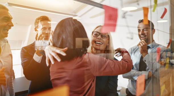 Businesswomen hugging while brainstorming with their team in an office