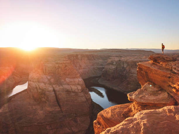 Lonely traveler standing on the edge over looking the Horseshoe band Horseshoe Bend Arizona is becoming an iconic image that represents the Grand Canyon in many visitors minds. View of horseshoe bend. horseshoe bend river stock pictures, royalty-free photos & images