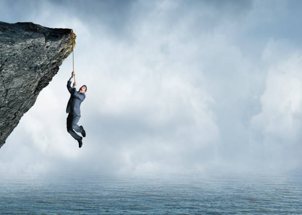 istock Businessman Hanging From Rope Off A Cliff 1070704108