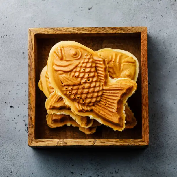 Taiyaki Japanese street food fish-shaped sweet filling waffle in wooden box on concrete background