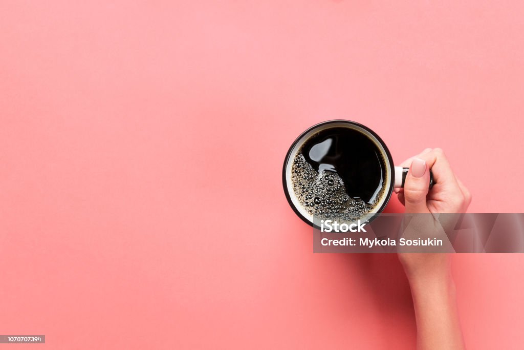 High angle of woman hands holding coffee mug on pink background Minimalistic style. Flat lay, top view isolated High angle of woman hands holding coffee mug on pink background Minimalistic style. Flat lay, top view isolated. Coffee - Drink Stock Photo