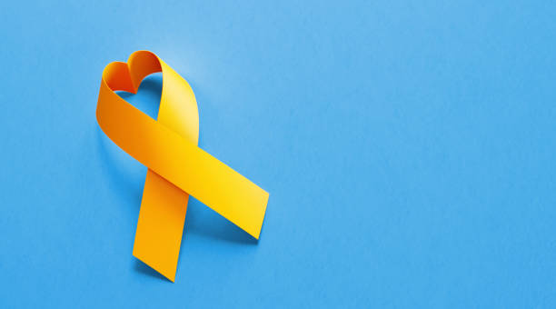 istock Heart Shaped Yellow Awareness Ribbon On Blue Background 1070709978