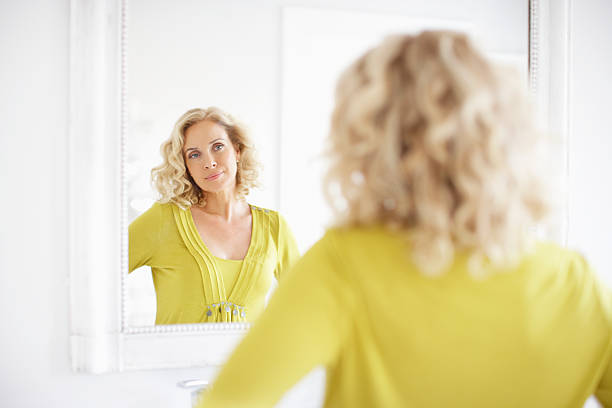 mature woman looking in mirror - mirror women looking reflection 뉴스 사진 이미지