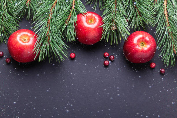 sfondo natalizio con rami di alberi, mele rosse e mirtilli rossi. tavolo in legno scuro - gift apple ribbon fruit foto e immagini stock