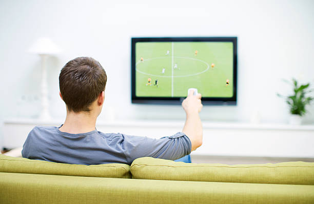 man watching football on television               - fernbedienung fotos stock-fotos und bilder
