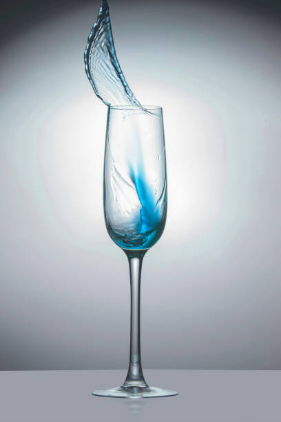 istock Transparent glass with light blue liquid jet up, close-up 1070721786