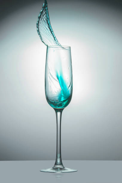 istock Transparent glass with light blue liquid jet up, close-up 1070721810