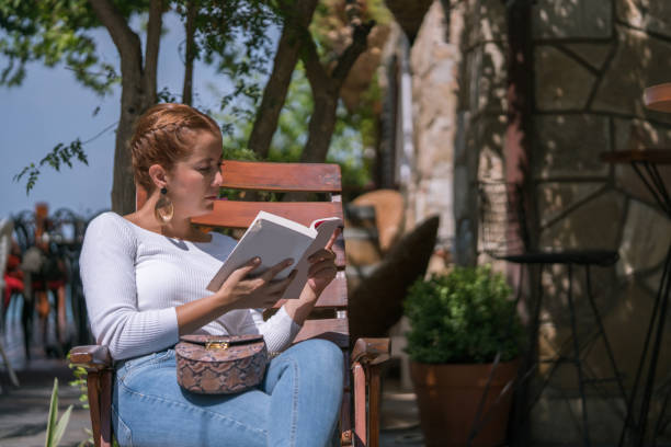 istock Mid adult woman reading book in front or back yard 1070728006