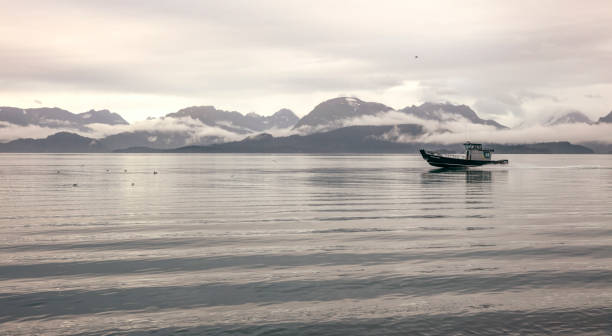 A fishing boat stands out of Noyo Harbor in Ft. Bragg, California at sunset.