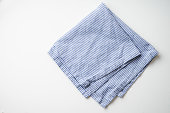 Striped blue and white textile napkin folded on white background. Food styling element
