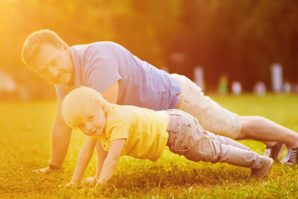 istock Little boy and his father doing plank exercise in sunny summer park 1070745742