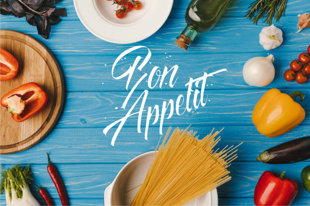vista dall'alto di pasta cruda e verdure su tavola blu, scritte bon appetit - bon appetite foto e immagini stock