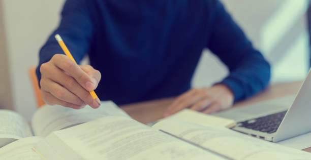 istock close up man hand using yellow pencil for writing or doing homework and research project in silent zone at university library ,international student and education day concept 1070751640