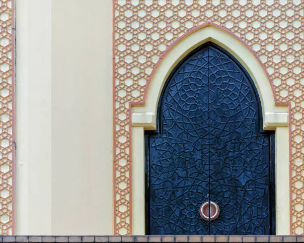 Traditional arabesque pattern on the wall, arched iron door with decorative ornament, Islamic architecture, vintage details, background with oriental decor.