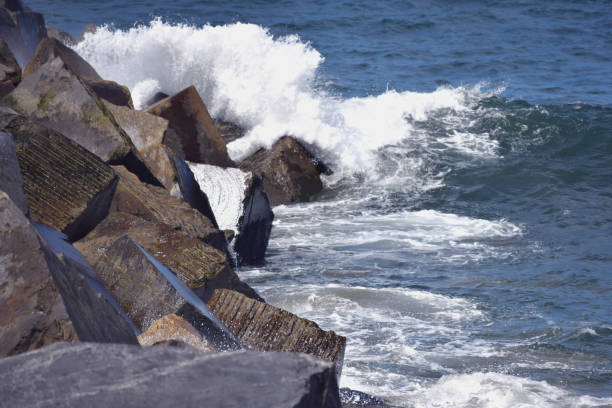 istock the waves breaking on the stones 1070782402