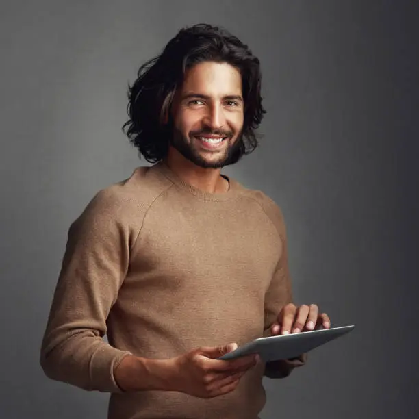 Studio shot of a handsome young man using a digital tablet against a gray background
