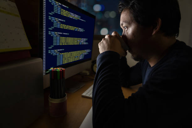istock Portrait of Asia Businessman sitting and working hard on the table with programming source code over computer screen in work place at late with serious action 1070800286