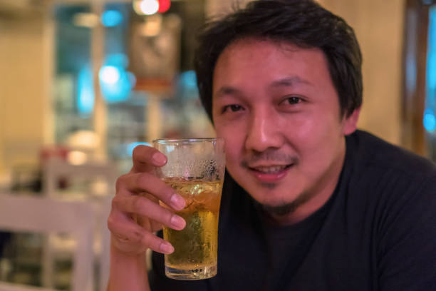 istock Asian young man in happiness action and drinking beer in pub and restaurant with low light place, relax and drink concept 1070800372