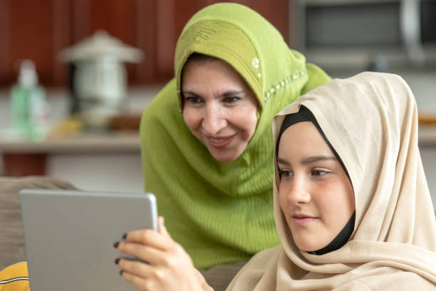 Muslim mature woman posing with her young daughter Muslim mature woman posing with her young daughter looking at a digital tablet moroccan girl stock pictures, royalty-free photos & images
