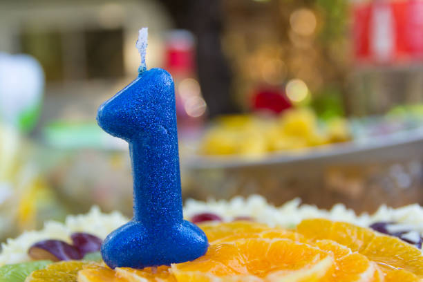 Candle in a shape of number one on a birthday cake stock photo