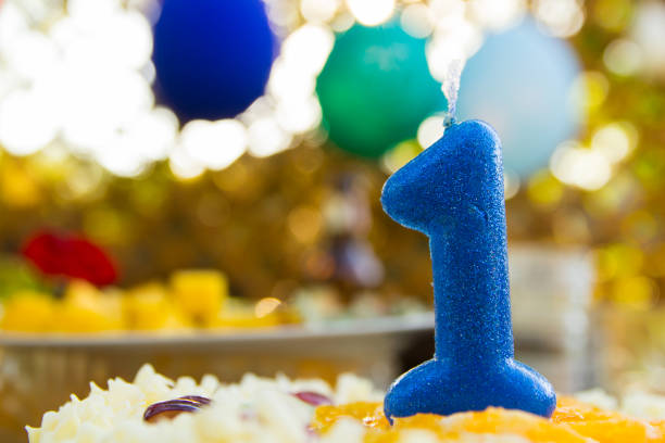 Candle in a shape of number one on a birthday cake stock photo