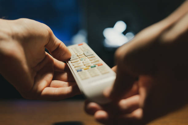 istock hands in the dark hold a tv remote and switch channels d 1070855386