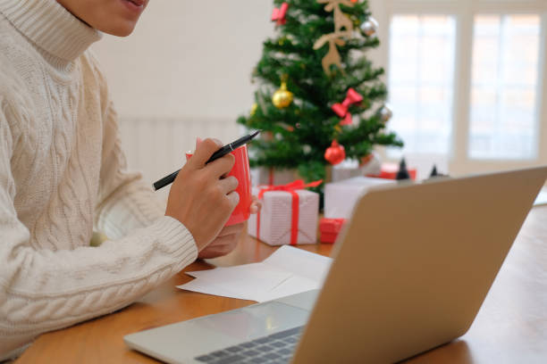 istock man holding coffee cup & using computer at home during christmas. xmas new year celebration 1070872352