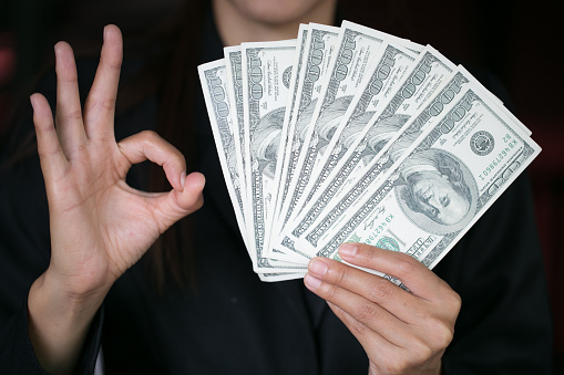 Business woman displaying a spread of cash over,  spending money or profit from business operations concept